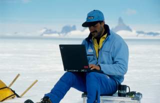Ralf Dujmovtis sitzt mit Laptop in der Arktis und teste die Technik. Das Foto ist aus dem Jahr 2000, der Laptop entsprechend veraltet.