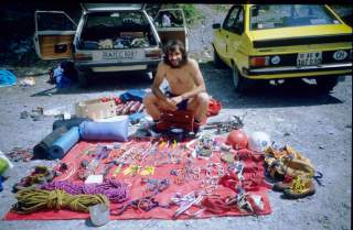 Der junge Ralf Dujmovits sitzt vor seinem ausgebreiteten Klettermaterial, im Hintergrund sind zwei alte Autos zu sehen. Das Bild wurde in den 80ern aufgenommen.
