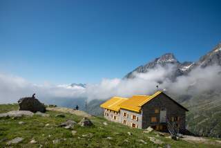 Berghütte mit Ausblick auf Gipfel und Wolken