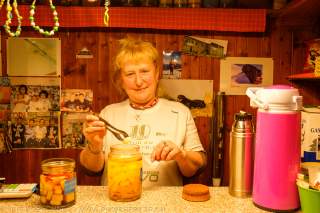 Frau steht hinter Hüttentheke und gibt Süßigkeiten aus