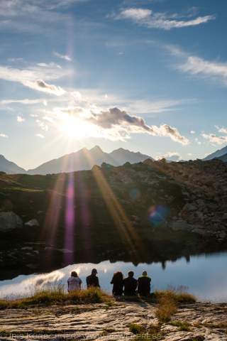 Gruppe sitzt am Bergsee in der Sonne
