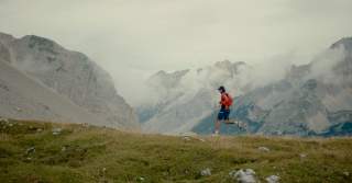 Junger Mann läuft durch wolkenverhangene Berge