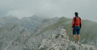 Mensch steht auf Felsen und blickt in die Berge