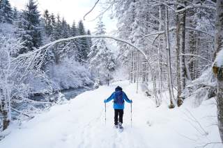 Schneeschuhwanderer läuft ein Bachbett entlang