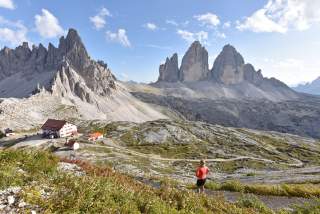Frau mit Aussicht auf Hütte und Drei Zinnen