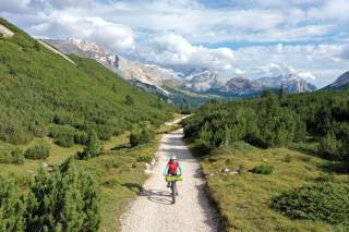 Moutainbikerin auf Schotterweg in Berglandschaft