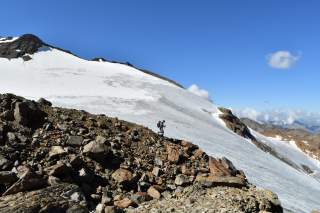 Wanderer auf Geröll vor Gletscher