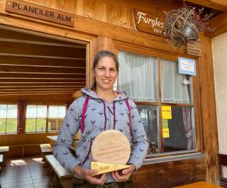 Frau steht vor einer Almhütte