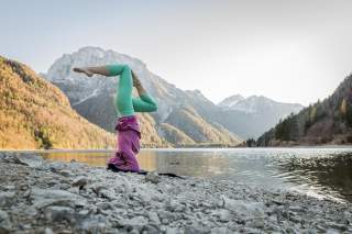 Frau macht Yoga an Ufer von Bergsee