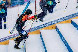 Skibergsteigerin rennt Treppen im Schnee hinauf.