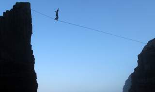 Mensch balanciert auf Highline zwischen zwei Felsen