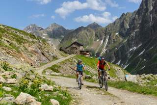 Zwei Menschen fahren auf MTBs von Berghütte weg