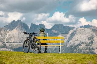 Mountainbiker sitz mit Blick auf das Civetta auf einer Bank