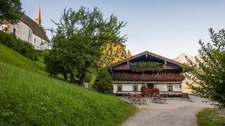 Links sieht man noch eine Kapelle, in der Mitte erstrahlt der mit Blumen geschmückte Berggasthof Streichen.