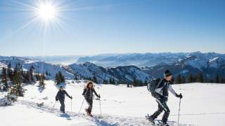 Skitouren*geherinnen auf dem verschneiten Geigelstein bei Sonnenschein.