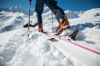 Mensch beim Skitourengehen mit Fokus auf der Skibindung.