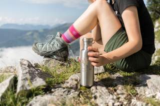 Wanderin während der Gipfelrast mit Trinkflasche