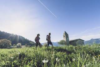 Zwei Wandernde auf Wiese vor alter Kirche