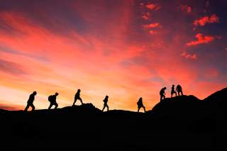 Gruppe von Wandernden auf Bergpfad im Sonnenuntergang