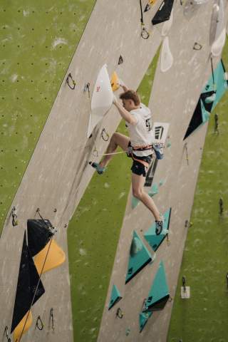 Ein Wettkampfkletterer im Vorstieg an einer künstlichen Kletterwand