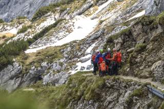 Gruppe von Bergrettern auf schmalem Wanderweg im Gebirge