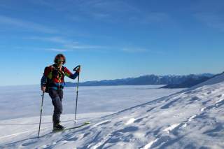 Bernhard Angerer über den Wolken, Aufstieg bei der Skidurchquerung. Strahlender Sonnenschein und blauer Himmel.
