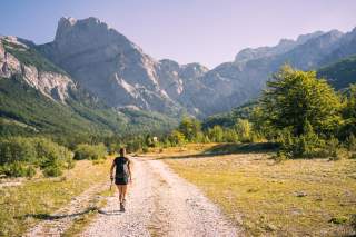 Frau wandert auf Schotterweg Richtung Berge