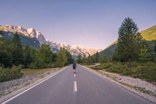 Frau wandert auf asphaltierter Straße in Berglandschaft