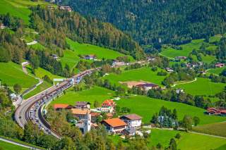 Stau auf einer Autobahn, die durch ein Alpental führt.