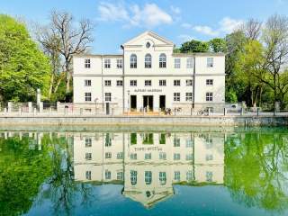 Museumsgebäude von Bäumen umrahmt und vor Wasser