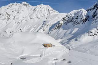 Ein Alpenvereinshütte steht inmitten verschneiter Gipfel