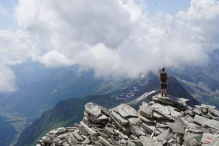 Wanderin steht in Blockgelände in den Bergen und genießt Aussicht
