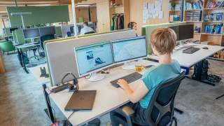 Menschen sitzen in Büro vor Computern
