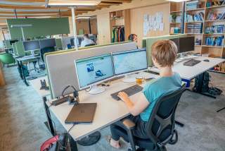 Menschen sitzen in Büro vor Computern
