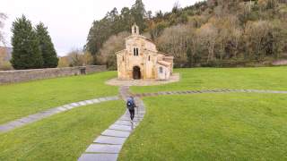 Wanderin läuft auf großen Steinplatten in Richtung einer historischen kleinen Kirche.