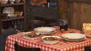 Gedeckter Tisch mit karierter Tischdecke und zwei Fleichgerichten.