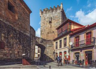Wanderpaar läuft durch ein altes Stadttor