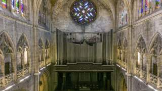 Alte Orgel, Buntglasfenster und steinerne Gänge im Innern einer alten Kirche.