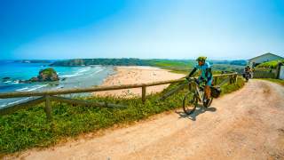 Radfahrer auf Mountainbike schaut über einen riesigen Sandstrand.