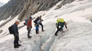 Ein Trainer erklärt vier Bergsteigern, wie man einen Pickel bei der Überquerung einer Gletscherspalte einsetzt.