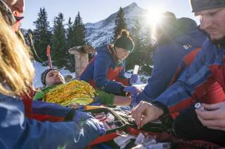 Personen von der Bergrettung versorgen Person in Winterlandschaft