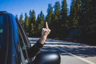 Autofahrer zeigt Mittelfinger aus geöffnetem Fenster