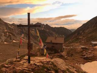 Hütte hinter Gipfelkreuz in Abendstimmung