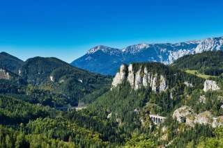 Mehrere Viadukte überspannen Täler in einer Berglandschaft.