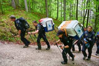 Die beiden Bartgeier werden in Käfigen auf dem Rücken von einer Rangerin und einem Polizisten getragen.