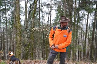 Vor Waldkulisse klärt Förster Christian Leitensdorfer gemeinsam mit seinem Jagdhund Schorschi über den heimischen Bergwald auf.