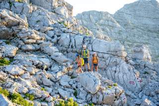 Drei Menschen in steigen in alpinem Gelände bergauf