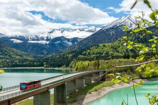 Bergsteigerbus fährt über Brücke am Sylvensteinstausee