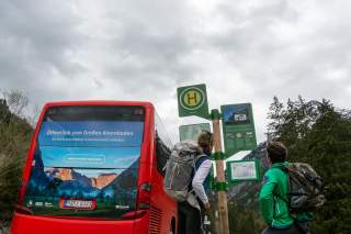 Zwei Menschen an Haltestelle des Bergbusses