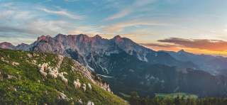 Ausblick auf die Bergkette der Steiner Alpen. Links erhebt sich der Berg. Schafe grasen darauf.